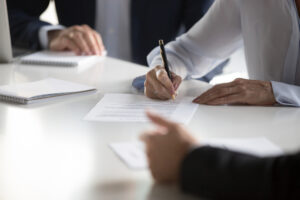 Businesspeople gathered together at business meeting after successful negotiations ready to sign agreement