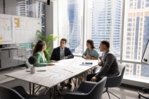Four multinational business partners gathered at conference table to discuss joint project details or updates