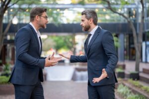 Businessmen fighting outdoor. Angry office workers dispute in city. Disagreed men partners